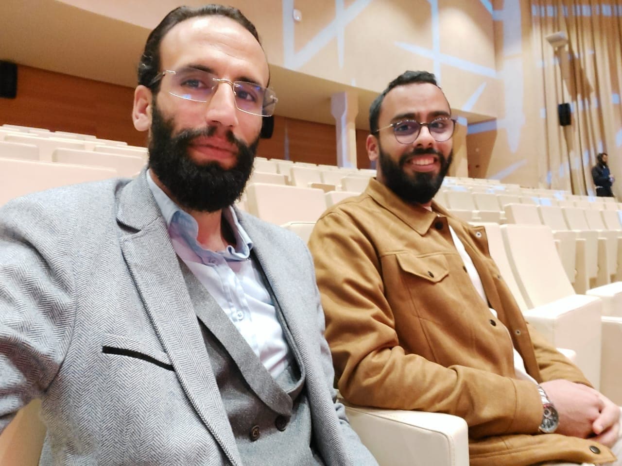 Ismail Essabar seated in an auditorium with a colleague